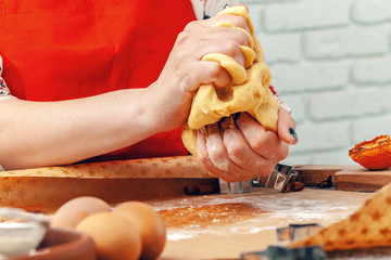 Woman's hands preparing dough for cookies close up