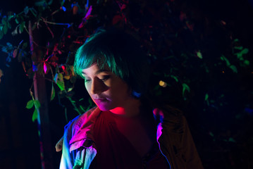 Young woman in the garden illuminated by multi-colored light.	