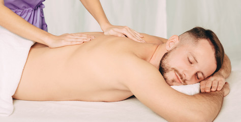 Obraz na płótnie Canvas Handsome man enjoying back massage at spa resort