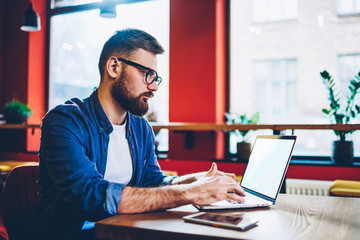 Fototapeta premium Skilled hipster guy working remotely with startup project on laptop device with copy space area for internet websites connected to 4g wireless for browsing web pages,concept of distance job