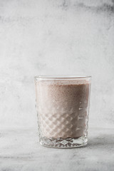 Glass of ice cocoa or chocolate milk isolated on bright marble background. Overhead view, copy space. Advertising for cafe menu. Coffee shop menu. Vertical photo.
