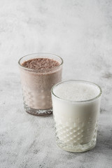 Two glasses of ice cocoa or chocolate milk isolated on bright marble background. Overhead view, copy space. Advertising for cafe menu. Coffee shop menu. Vertical photo.