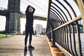 Young guy warming up arm muscles embankment