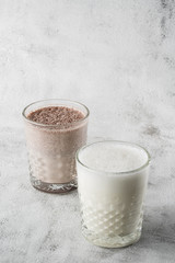 Two glasses of ice cocoa or chocolate milk isolated on bright marble background. Overhead view, copy space. Advertising for cafe menu. Coffee shop menu. Vertical photo.