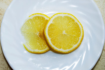 Two slices of lemon  on a white saucer, top view