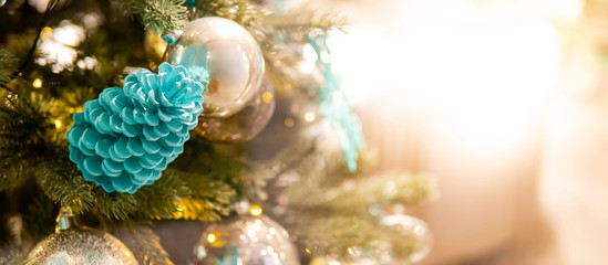 Christmas decoration for festive season. Light blue pine cone and shiny Christmas ball on branch of Christmas tree with bright copy space.