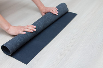 woman's hands unwrap yoga mat at home for doing yoga
