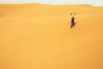 Fototapeta na wymiar Girl holding a snowdboard in sand dunes of Abu Dhabi ready to sandboard
