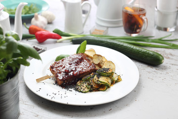 Seitan, vegetarian high-protein meat baked in soy sauce, served with baked potato slices, cucumbers and black sesame seeds.