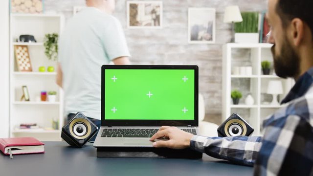Man looking at modern laptop with green screen