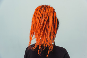 Girl with red fire dreadlocks gathered in a tail on a white background rear view. A young woman...