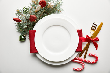 top view of festive Christmas table setting on white background with decoration, pine branch and...