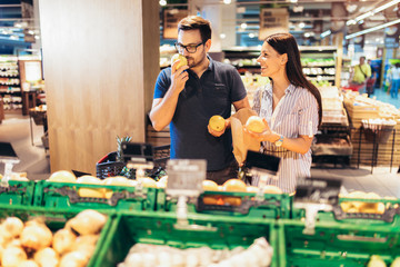 Happy couple in supermarket buying fresh fruit together