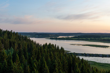 View from the mountain to the coniferous forest and lake. Sunset on Mount Paaso. Karelia
