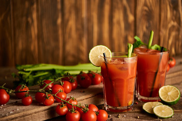  selective focus of bloody mary cocktail in glasses on wooden background with salt, pepper, lime, tomatoes and celery © LIGHTFIELD STUDIOS