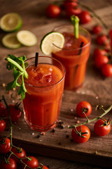 selective focus of bloody mary cocktail in glasses on wooden background with salt, pepper, tomatoes and celery