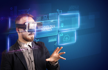 Businessman looking through Virtual Reality glasses with TECHNOLOGY TRENDS inscription, new technology concept