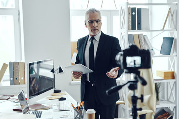 Fototapeta premium Senior man in elegant business suit sharing his business experience while making social media video