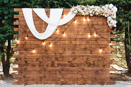 Rustic wooden wedding arch with retro garland decorated with flowers for wedding ceremony newlyweds
