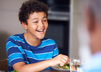 Close Up Of Boy As Multi-Generation Mixed Race Family Eat Meal Around Table At Home Together