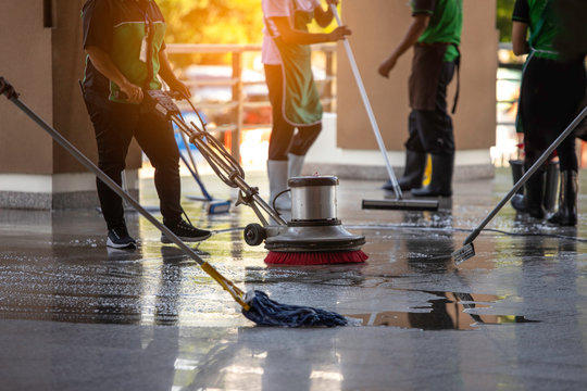 The workers cleaning floor exterior walkway using polishing machine and chemical or acid