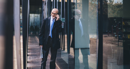 Mature cheerful businessman standing outside building