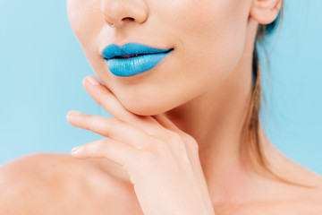 cropped view of naked beautiful woman with blue lips posing with hand near face isolated on blue