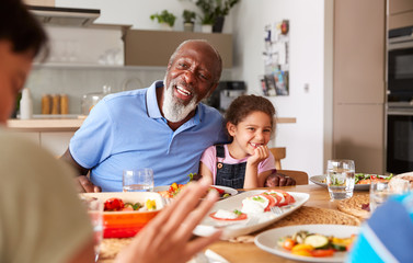 Multi-Generation Mixed Race Family Eating Meal Around Table At Home Together