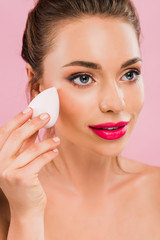 naked beautiful woman with pink lips holding makeup sponge isolated on pink