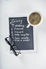 Chalk board with list of tasks, ideas, task for Giving Tuesday. Notes to various helping on Tuesday. International Charity Aid Day concept. White desktop flatlay copy space