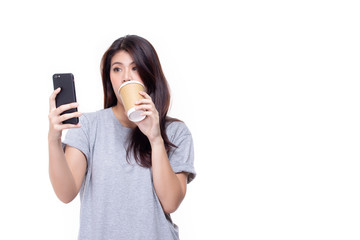 Pretty young asian woman standing isolated on white background. Beautiful girl in gray casual shirt with phone and takeaway coffee cup.