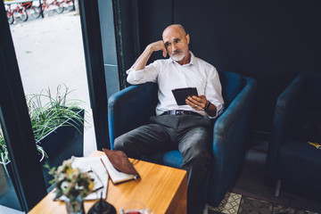 Old upset male browsing tablet