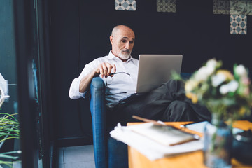 Elderly man working on laptop with glasses off