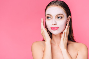 naked beautiful woman in facial mask with hands near face isolated on pink