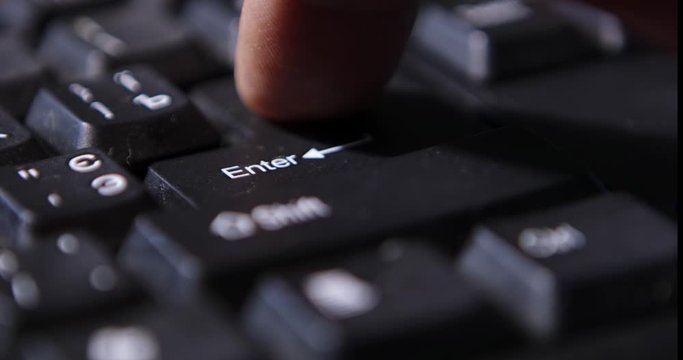 The hand is typing a black keyboard on a white table with blue lights.