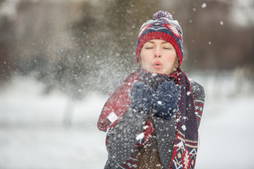 Happy beautiful woman having fun with snow outdoors in winter scenery