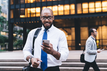 Curious black businessman using smartphone - obrazy, fototapety, plakaty