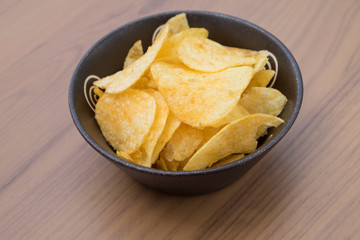 Potato chips on  plate on wood table