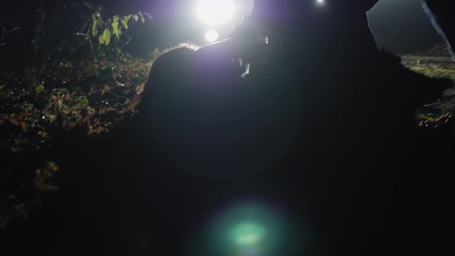Aggressive man knocks down a girl running away from him, shows violence, hits and tries to kill. People fighting against the background of headlights of a car. Handheld 4k shot