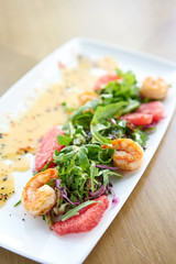 Delicious dish with grilled shrimps, slice grapefruit and arugula salad and spicy fried prawns. Restaurant menu, natural and organic food concept.