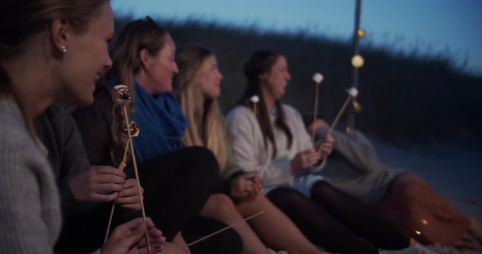 Girlfriends having a good time around campfire on the beach. Cinematic lifestyle scene perfect for travel or corporate video projects.