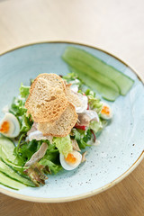 Olivier salad with Lamb tongue, salted cucumber, quail egg. Wooden table background. Menu restaurant. Russian traditional salad