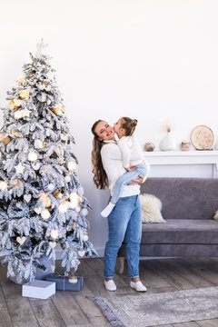 Happy mother and daughter decorating Christmas fir-tree in living room. Christmas tree background.