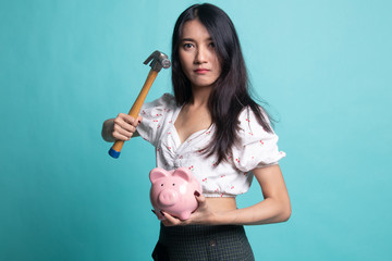 Asian woman with pig coin bank and hammer