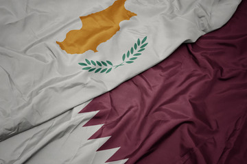 waving colorful flag of qatar and national flag of cyprus.