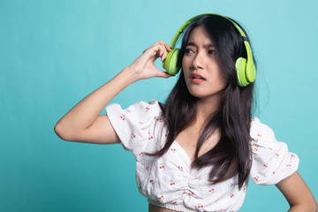 Too loud.  portrait of  young asian woman  holding  headphones and making unhappy face.