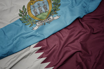 waving colorful flag of qatar and national flag of san marino.