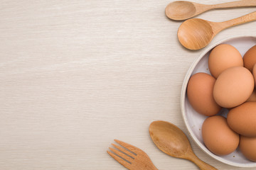 Fresh eggs on a bowl rustic background, wood spoon, weighing apparatus.The top view. View from above.
