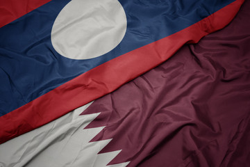 waving colorful flag of qatar and national flag of laos.