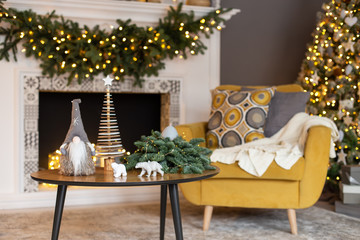 Two soft chairs and journal table stand in front of christmass decorated firplace. Soft focus